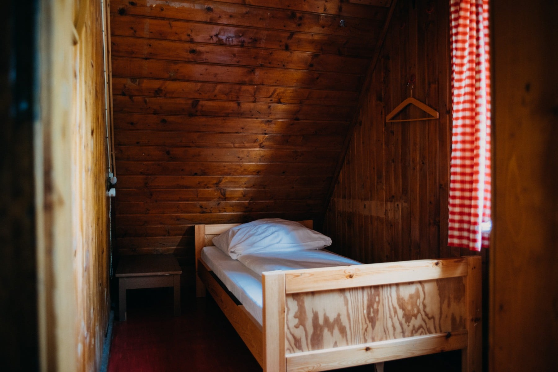 Ein Bett unter der Dachschräge in einem holzvertäfelten Zimmer.